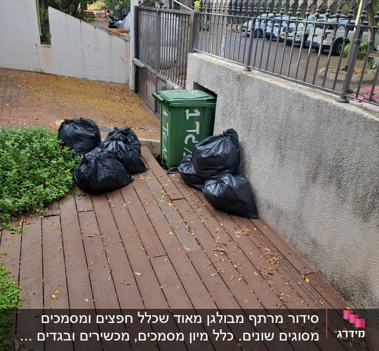 שקי אשפה שחורים המיועדים לפינוי לצד פח אשפה בחצר